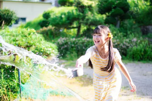 庭で打ち水をする子ども
