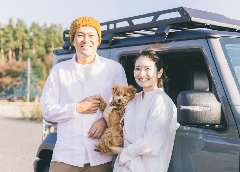 自動車のそばに立つ夫婦と犬